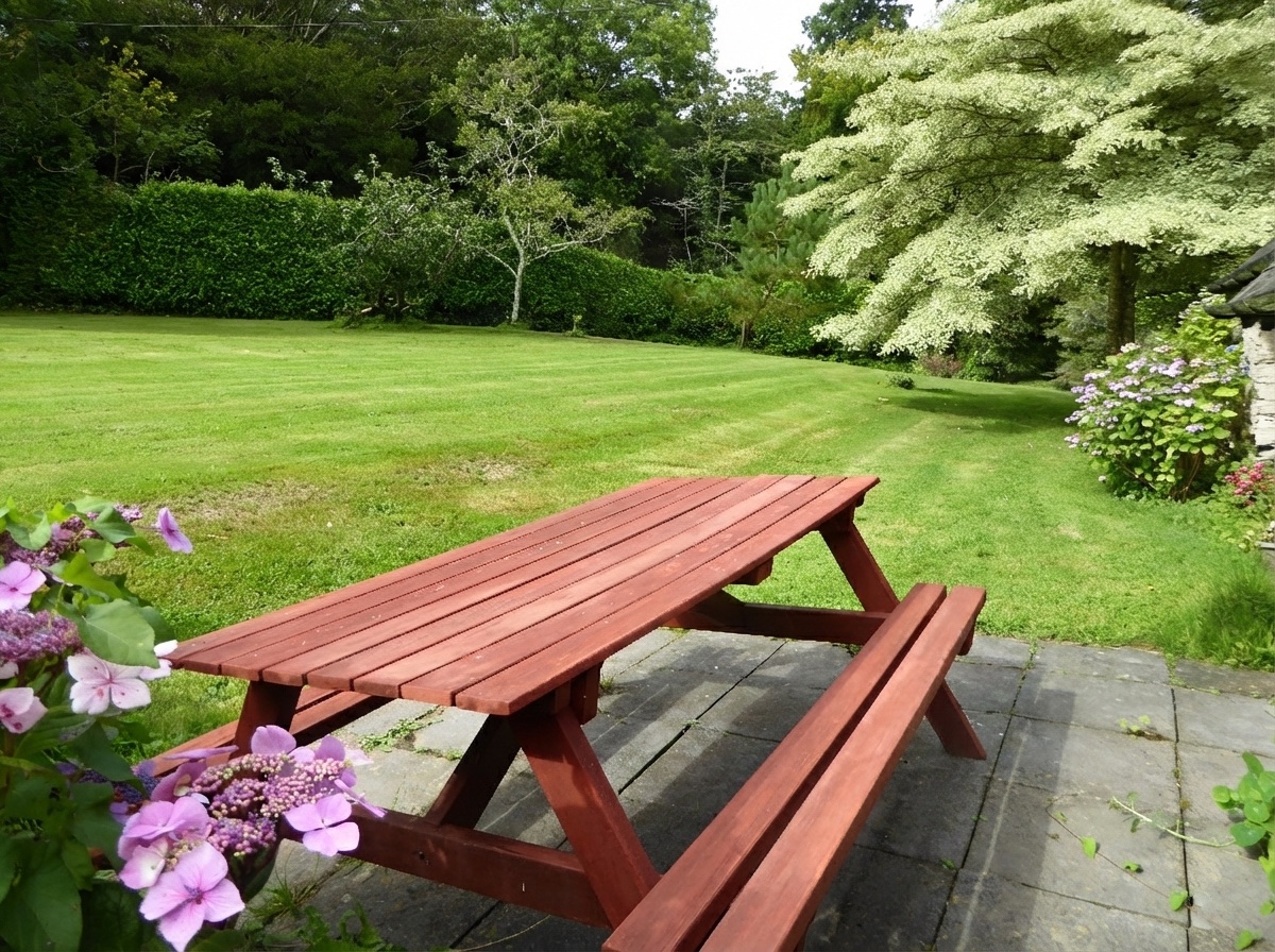 Wooden picnic table on the Coach House patio overlooking lawn with mature trees